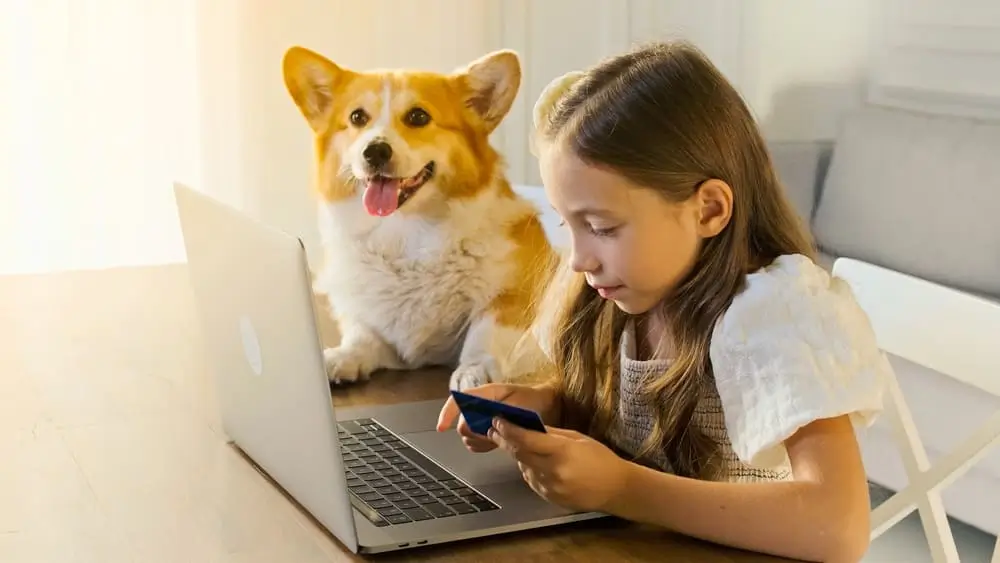 una niña con un perro mirando un computador y aprendiendo de educación financiera