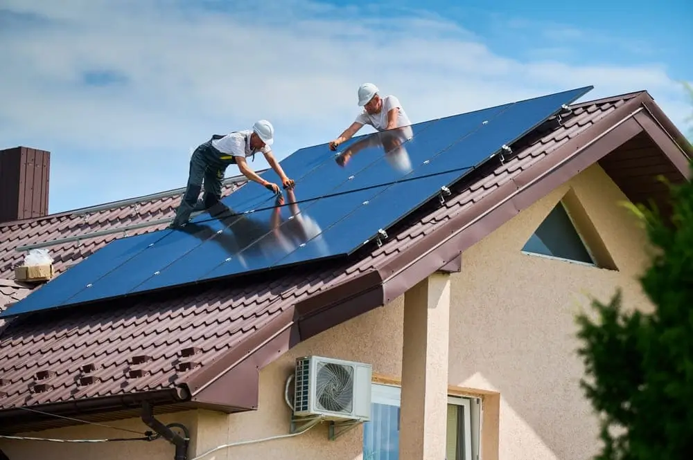 Dos hombres instalando paneles solares en el techo de una casa