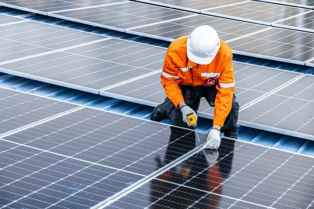 Un hombre en un techo instalando paneles solares