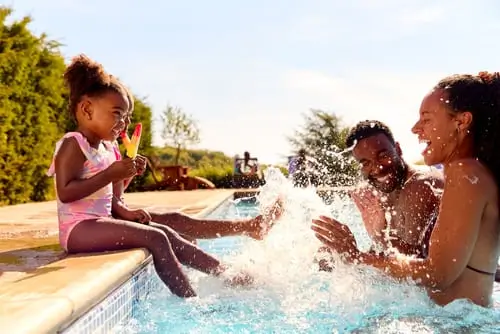 Dos papás con su hija en una piscina